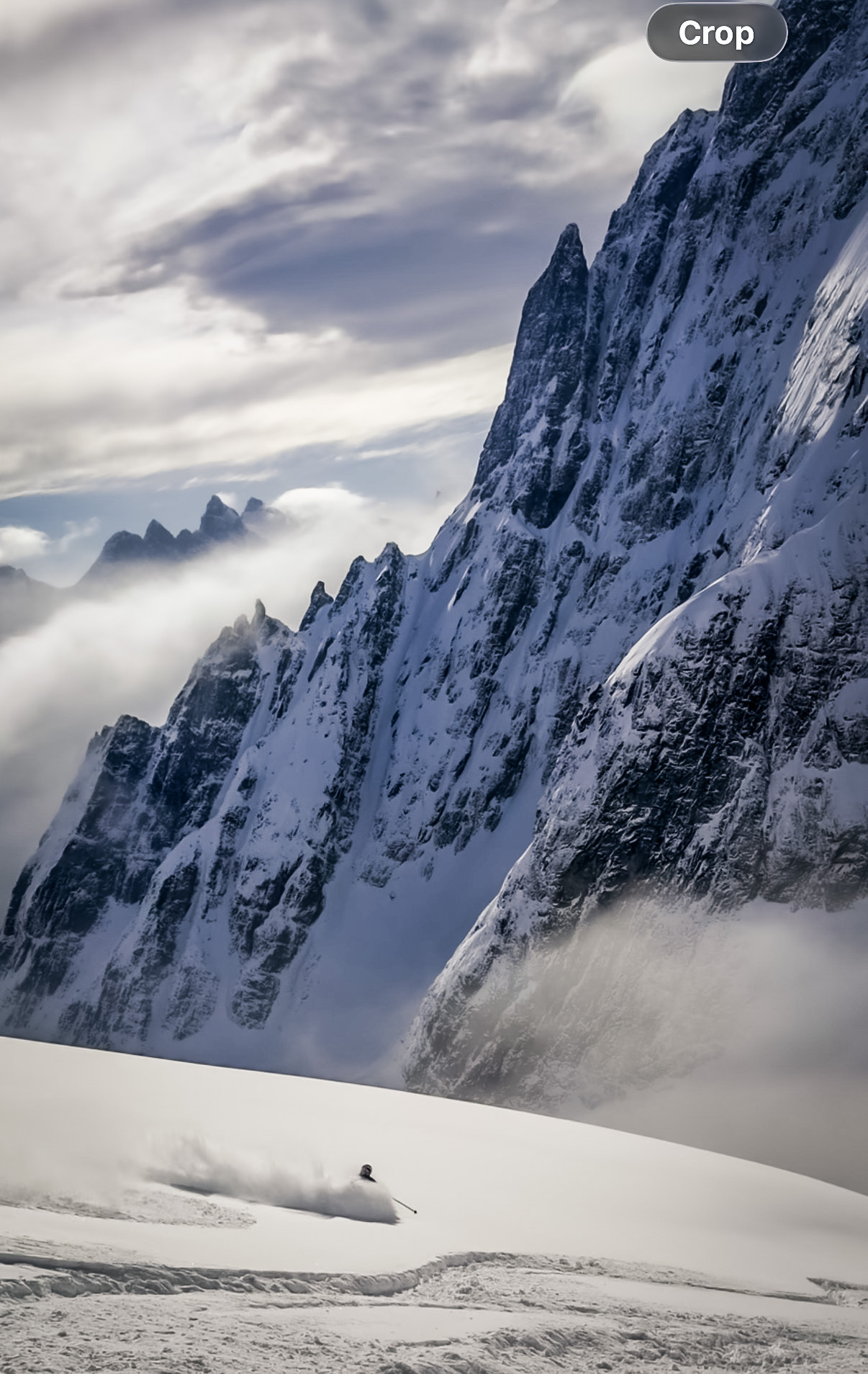 Skier beneath steep Alaskan peaks