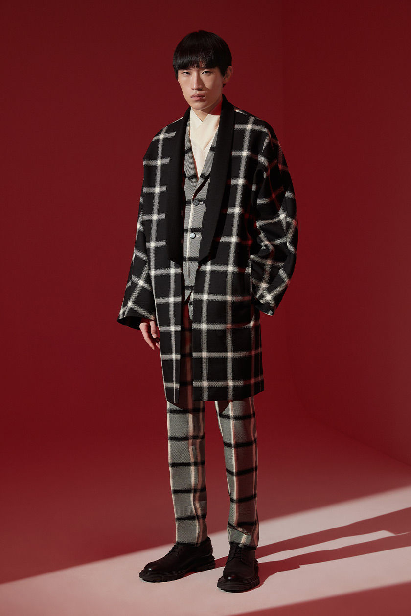 Il check ormai elemento identificativo della collezioni KB HONG, per questa stagione è proposto in tre tonalità: bianco, nero e grigio.Il classico cappotto viene reinterpretato in chiave moderna, ricordando un ampio kimono. Il look viene completato dall'iconica camicia con collo incrociato e dl pantalone con fit regular.