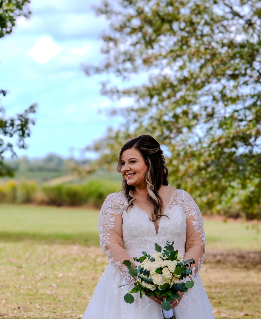 Bride standing in a field with trees