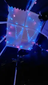 Acoustic panel ceiling in a studio with blue and pink lights.