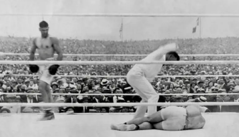 Dempsey stalks a prostrate Carpentier as referee Ertle counts to 10.