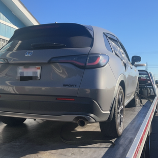 Gray car secured on flatbed tow truck parked in Irvine California daytime