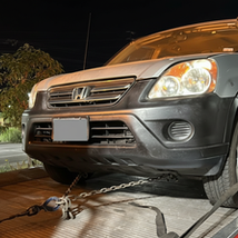 Gray Honda secured on flatbed tow truck at night in Orange County California