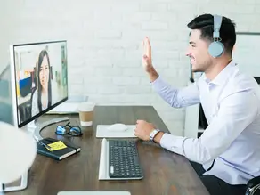 A remote sales professional with headphones participating in a video conference with a diverse team on a computer screen, highlighting how nearshore staffing helps companies scale fast in their time zone.