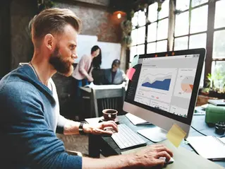 Professional analyzing a dashboard with area charts and pie graphs on a computer monitor, illustrating the real numbers behind tech revenue and a deep dive into compensation by Confetti Recruiting.