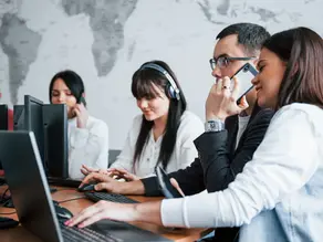 A group of diverse professionals working together in an outsourced call center, illustrating how Confetti Recruitment provides sales outsourcing solutions to help businesses expand their reach and dominate their market.