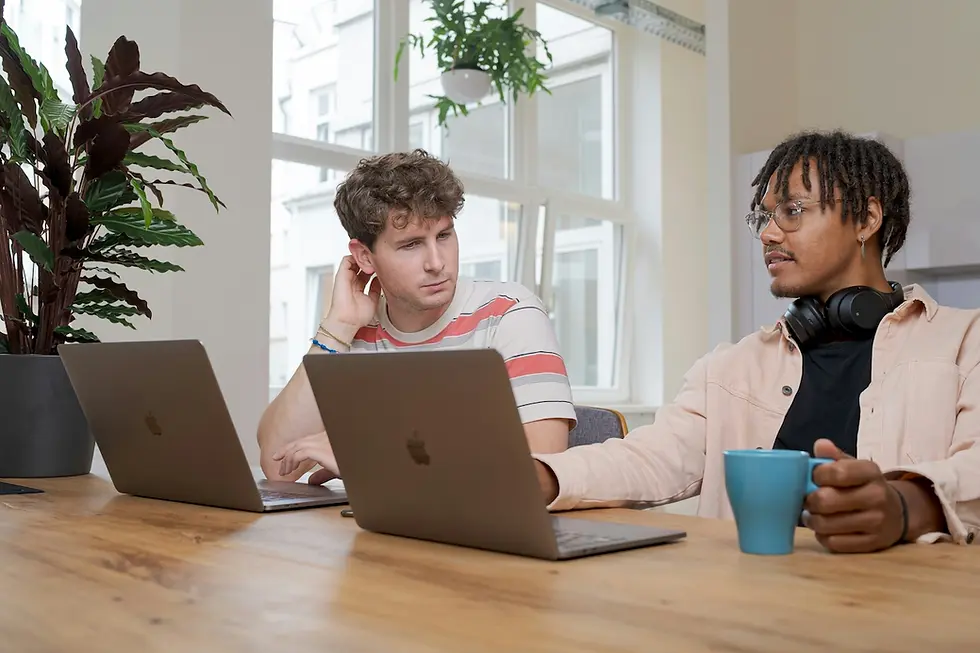 Two software professionals discussing strategy at a wooden desk with laptops, illustrating the anatomy of a dealmaker and inside the life of a software closer by Confetti Recruiting.