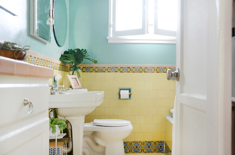 An open door reveals a small yellow bathroom. This photo is part of a blog for eConserve, a multifamily water company.