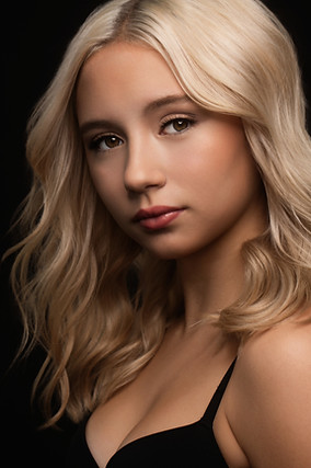 A teen girl with long blonde hair against a black backdrop, glam portrait, model portfolio