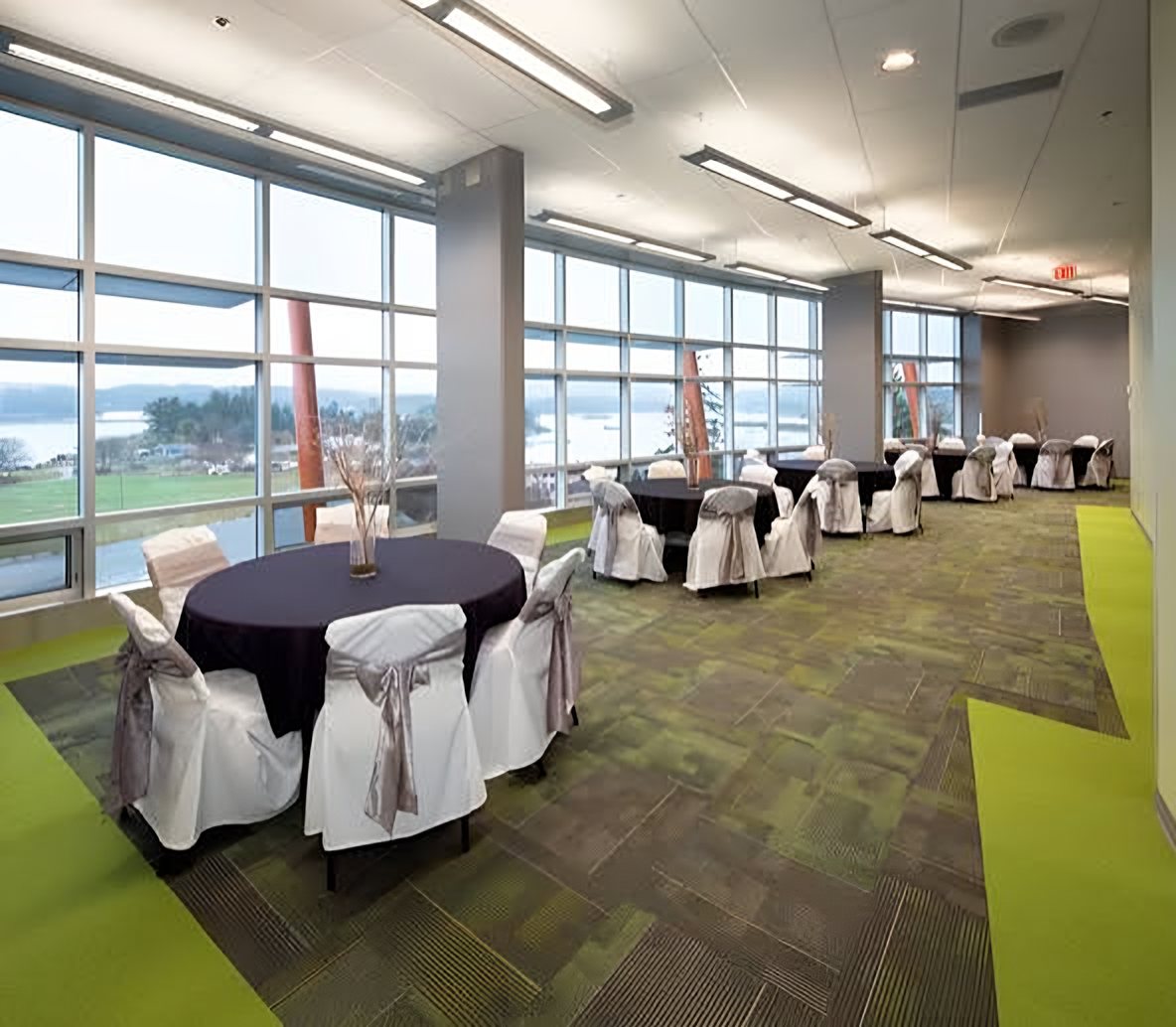The Oceanview Conference Room set with round tables in black linens and white chair covers, with floor-to-ceiling windows looking out over the water
