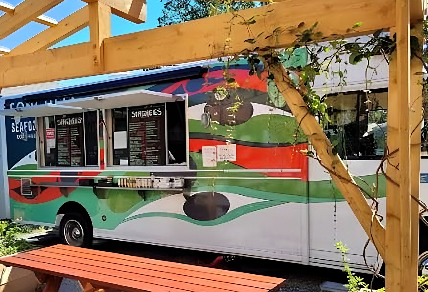 The Songhees food truck with its colourful octopus wrap, parked behind a wooden pergola and picnic table