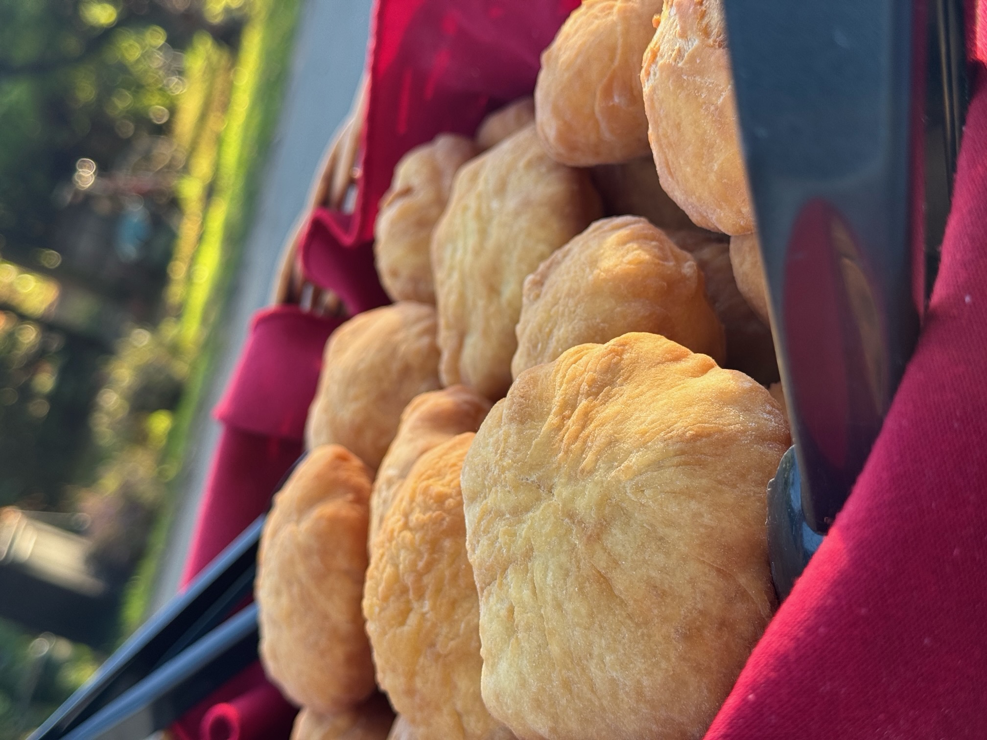 Fresh golden bannock piled in a red-lined basket, served outdoors