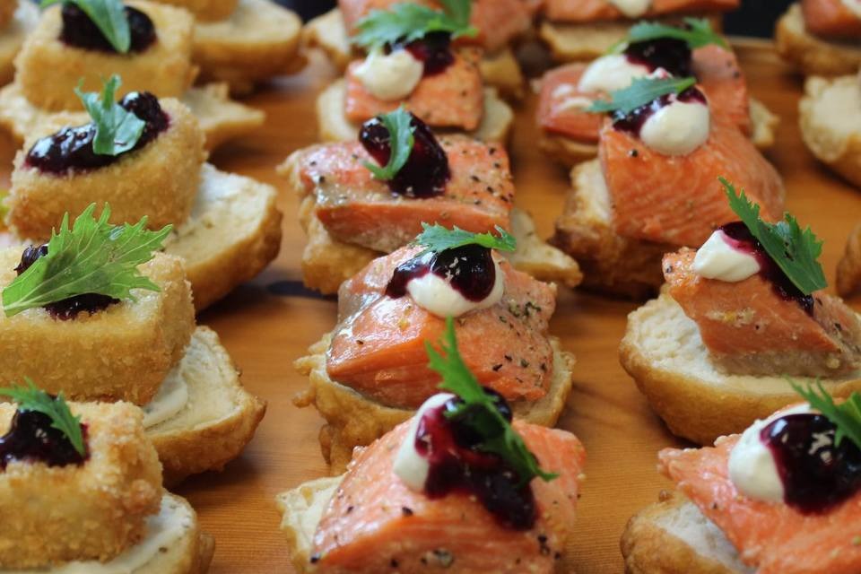 Canapés of wild salmon on bannock with crème fraîche, berry compote and fresh greens, beside crispy goat cheese bites
