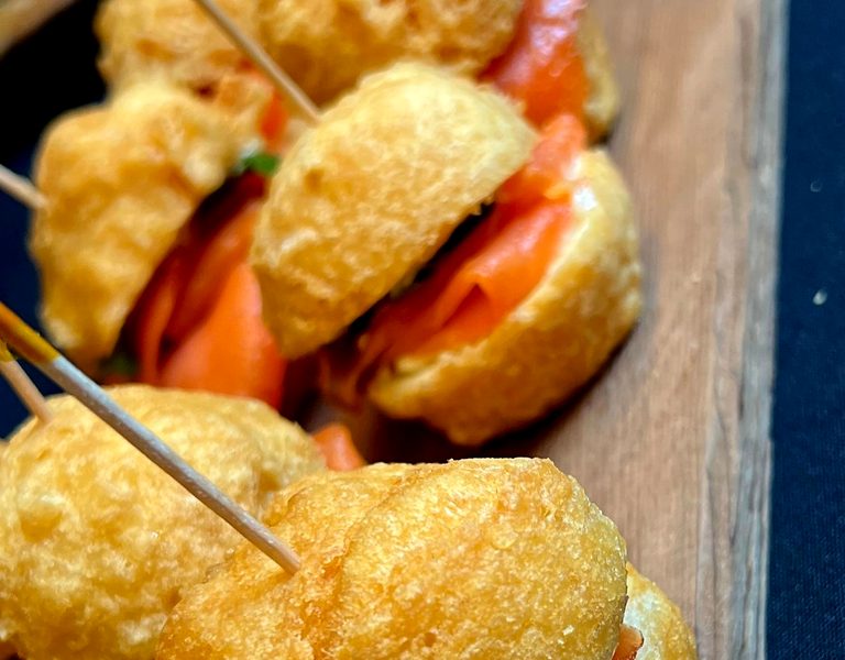 Golden bannock sliders filled with wild salmon and candied red onion, served on a cedar board