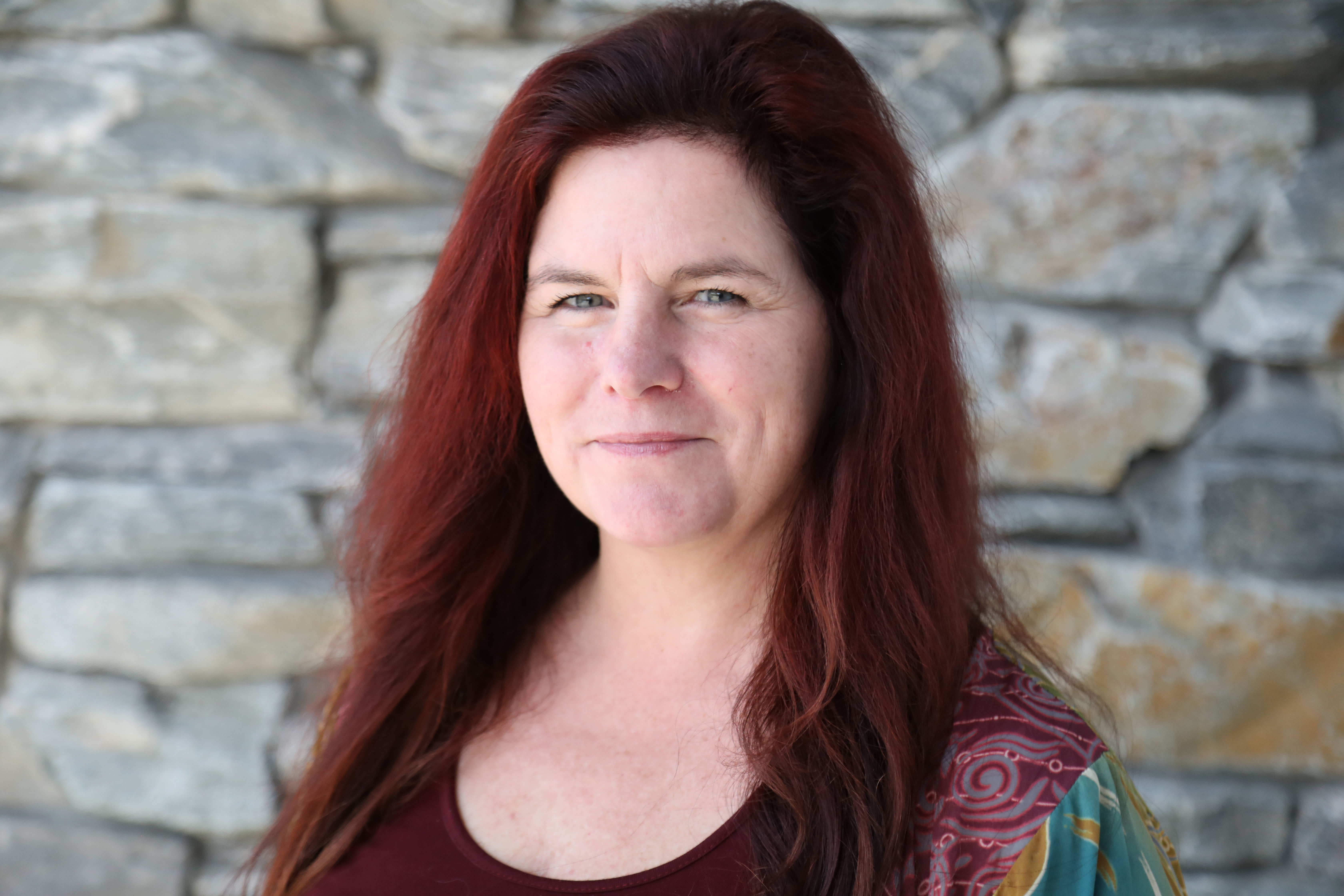 Catherine Davies smiling in front of a stone wall