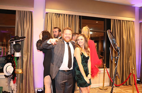Guests dressed in formal attire posing and laughing at an interactive photo booth experien