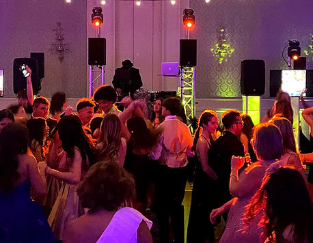 Lively crowd dancing on a packed floor at a premium event with a professional DJ booth, li
