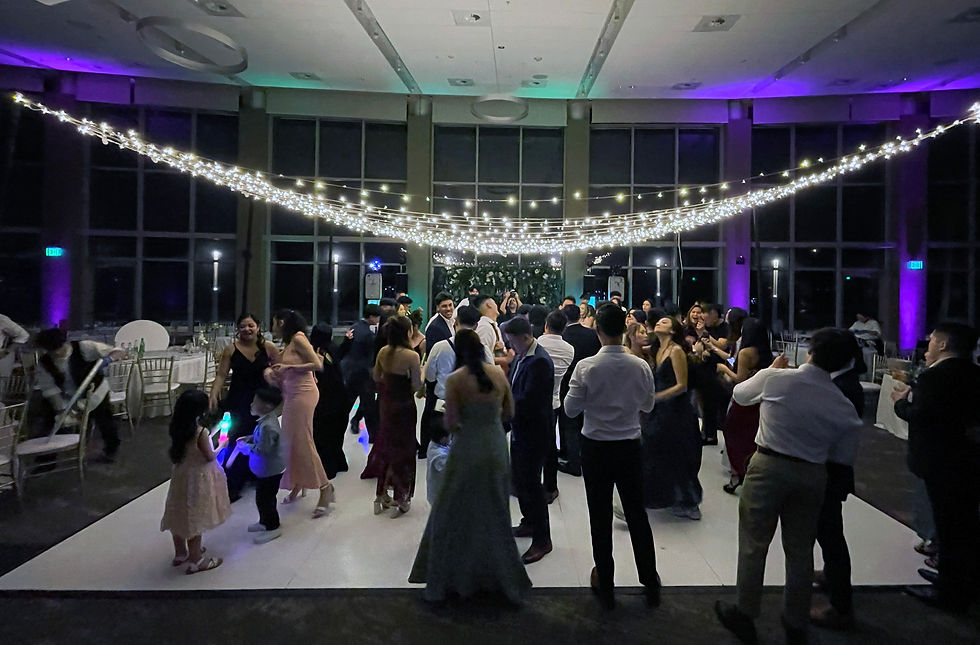 Stunning upscale venue setup with a clean white dance floor, purple accent uplighting, and a beautiful canopy of fairy string lights hanging over the guests.