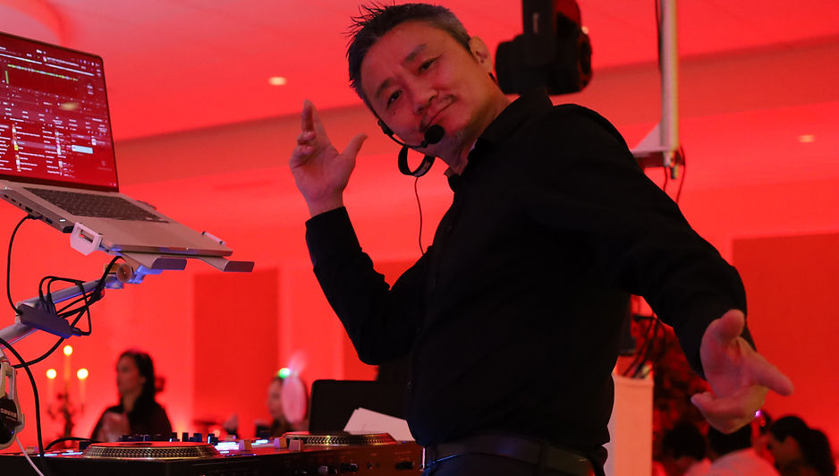 Professional party DJ mixing music and engaging the crowd under vibrant red event lighting in Central Florida.