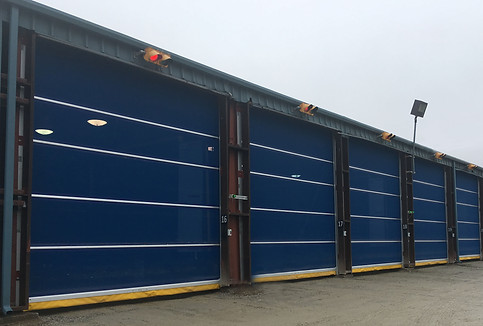picture of several doors in a row, outside facing doors, blue in colour with a yellow vinyl bottom safety edge