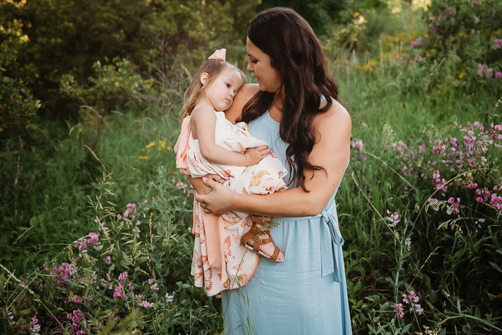 Mother holding her toddler daughter surrounded by wildflowers during a family photography session in Central Florida.