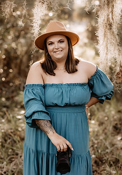 Woman in a teal off the shoulder dress smiling outdoors in natural light during a portrait session in Central Florida