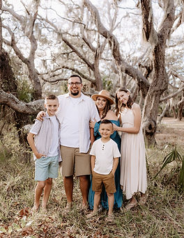 Family of 5 standing together beneath spanish moss oak trees during a portrait session in Central Florida.