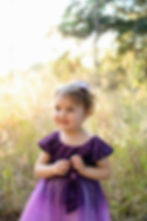 Little girl smiling in a golden sunlit field during a family photography session in Central Florida.