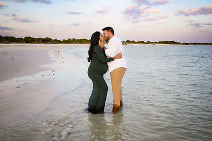 couples sharing a kiss during a maternity photoshoot at honeymoon island, florida