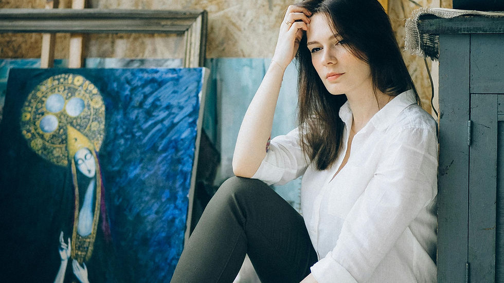 Woman sitting in front of art supplies looking overwhelmed