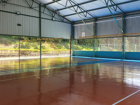 Quadra de peteca coberta do Clube Campestre Gremig em Contagem, com piso esportivo azul e laranja — estrutura moderna e área de lazer para associados.2