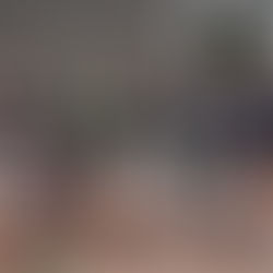 A diverse group of people, some standing and some kneeling, wear "Communities for Youth" shirts outside a building, smiling and posing together.