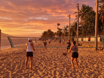 Beach tennis na Praia de Itaguassu, Ilhabela! O pôr do sol pinta o céu enquanto moradores aproveitam o jogo. Energia e beleza natural se encontram neste paraíso.