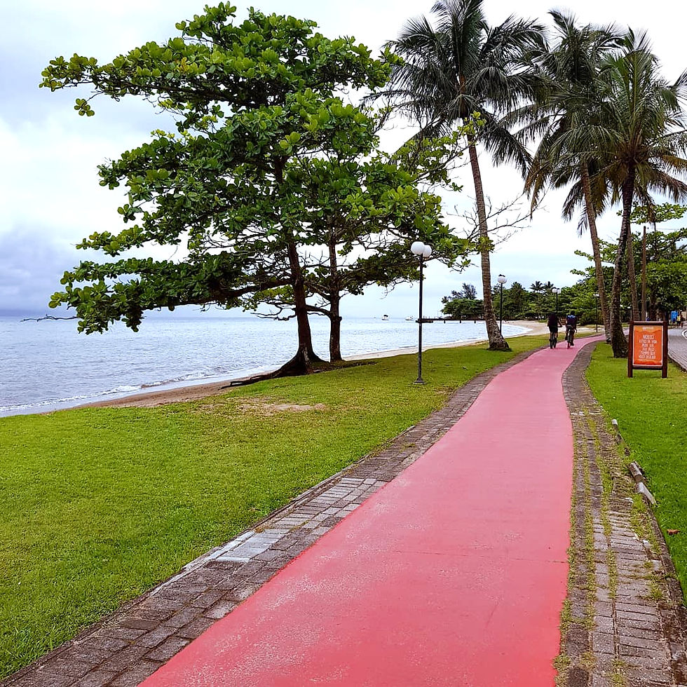 Ciclovia em Ilhabela com pessoas pedalando e a paisagem da ilha ao fundo