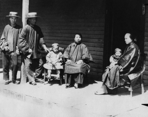 Group portrait of an unidentified Chinese family; image shows a family in their typical clothing circa 1892; the Chinese community in Anaheim was located south of Chartres, between Los Angeles (now Anaheim Blvd.) and Lemon Streets; most of the Chinese worked as laborers and/or sold produce to the citizens of Anaheim.