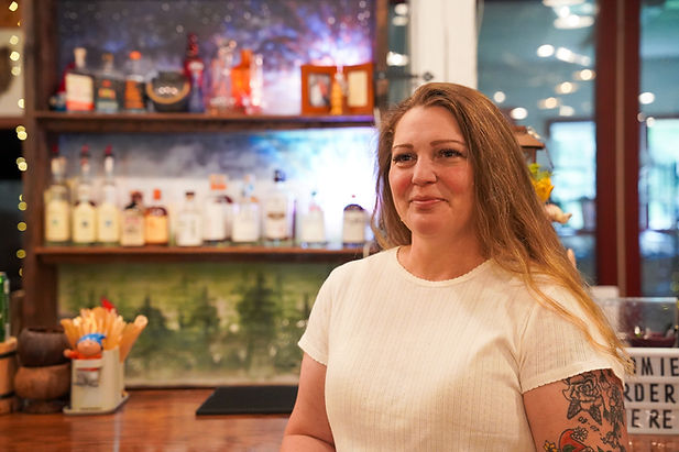 Gnomies owner stands in front of a colorfuly lit bar