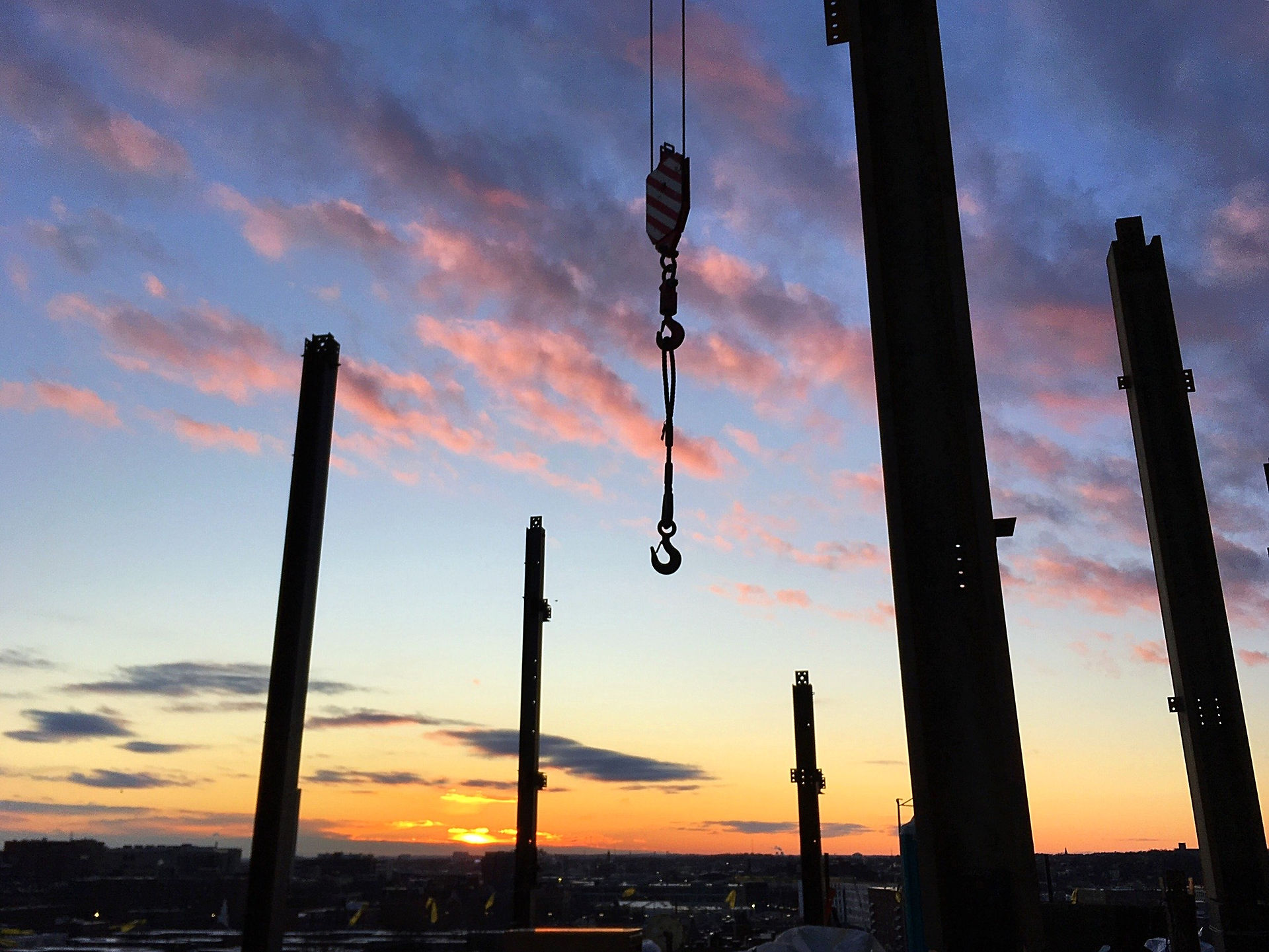 Job site photo of I-beams silhouetted against sunset skyline