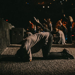 A group of people deep in worship, hands raised in surrender and reverence, capturing a moment of spiritual connection and devotion. The atmosphere is filled with warmth and divine presence, as individuals are fully immersed in an experience of faith, prayer, and surrender. The image radiates peace, unity, and the powerful transformation that comes from worship.