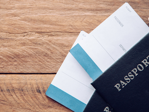 Two passports with plane tickets sticking out the top of them. There is a small model plane to the right above the passports.