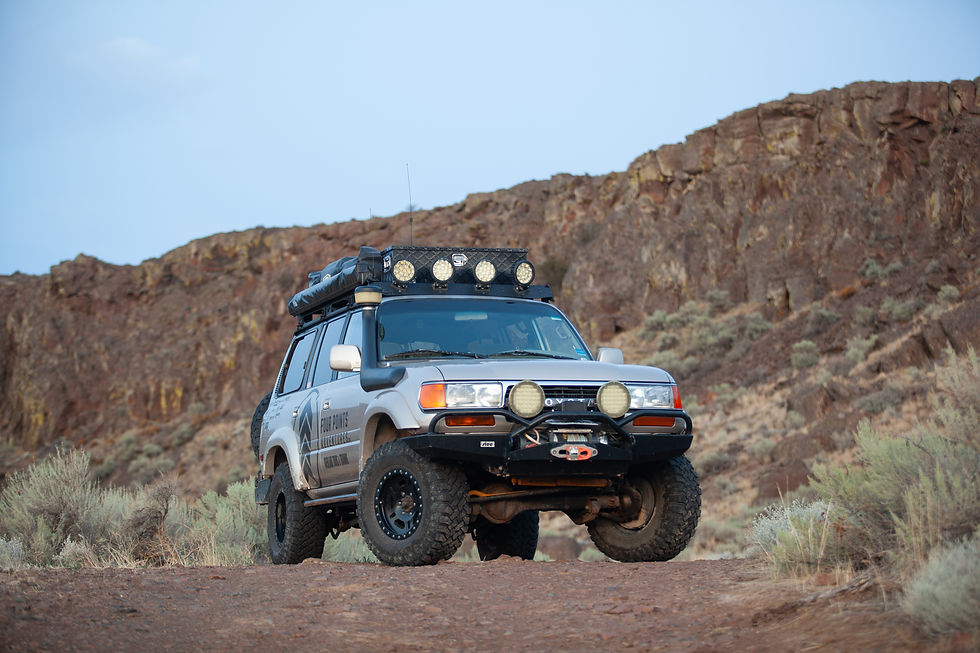 Off-road SUV with roof lights on a rocky desert trail, Four Points branding on the side, under a pale blue sky.