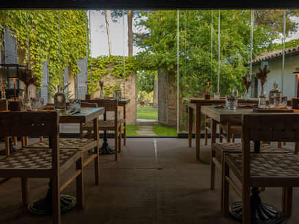 Glass-enclosed dining room at UMAMI restaurant, MasQi, opening onto the ivy-covered courtyard