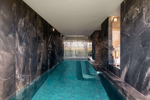 Indoor pool with black marble walls and turquoise water.