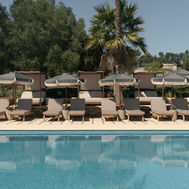 Outdoor swimming pool at Shanti-Som Algarve, lined with loungers and parasols beneath the palms