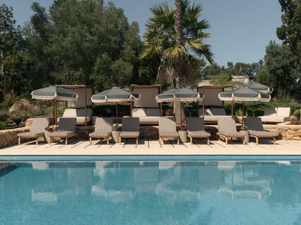 Outdoor swimming pool at Shanti-Som Algarve, lined with loungers and parasols beneath the palms