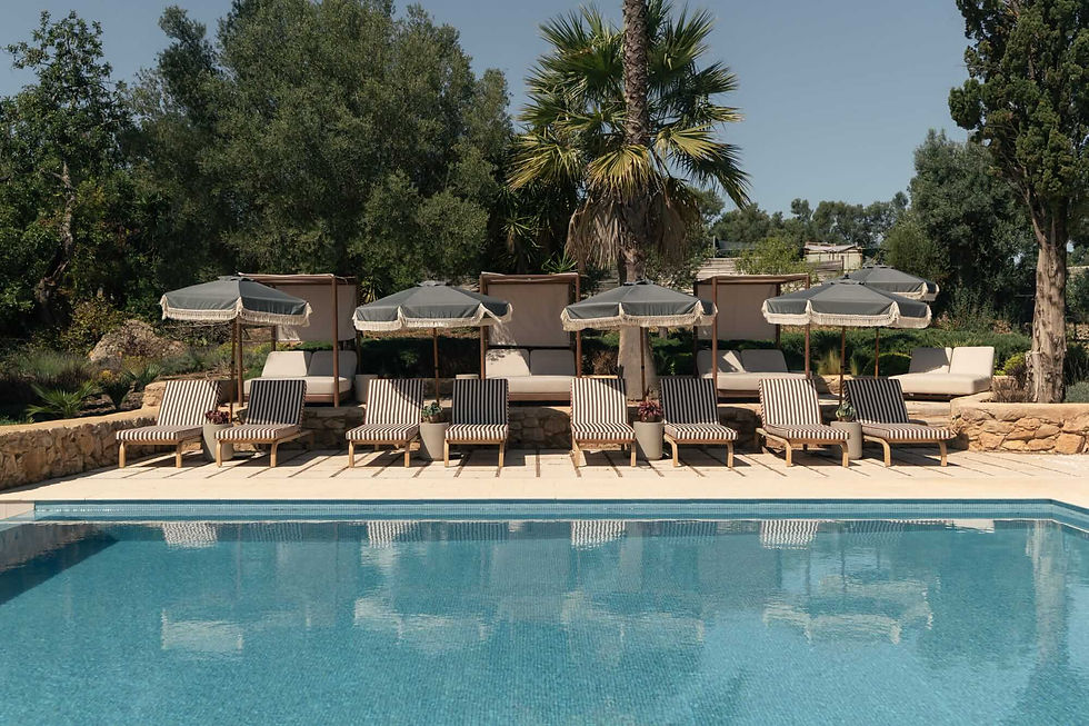 Outdoor swimming pool at Shanti-Som Algarve, lined with loungers and parasols beneath the palms