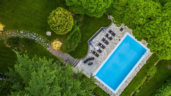 Aerial view of the outdoor swimming pool surrounded by lush gardens at Villa Eden Merano