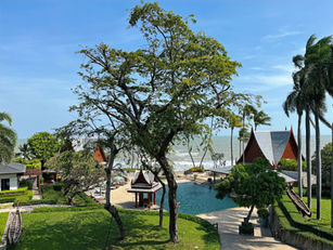 Tranquil poolside view at Chiva-Som Health Resort surrounded by palm trees and Thai-style architecture.