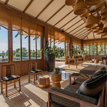 Natural, serene interior of Rakxa Integrative Wellness retreat, featuring wooden furnishings, woven baskets, and large windows overlooking lush greenery and a calm waterway.