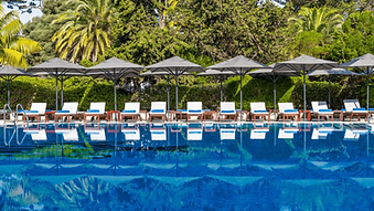 Sun loungers and parasols by the outdoor pool at Hotel Palácio Estoril Cascais