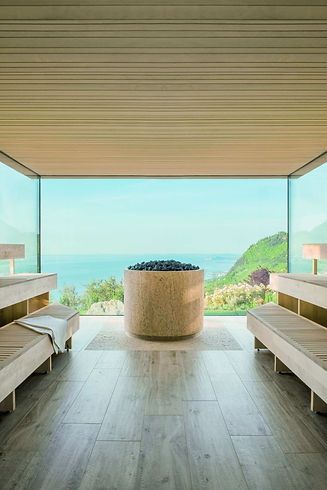 Panoramic sauna at Lefay Resort & SPA Lago di Garda with floor-to-ceiling windows overlooking Lake Garda and lush hillsides.